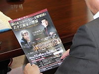 原田さんのコンサートのパンフレットを手にする濱野区長
