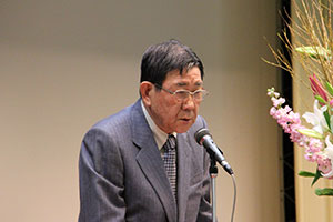 卒業式で来賓あいさつする品川区民健康づくり推進協議会の上野会長