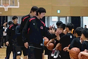 バスケットチームの選手とハイタッチする小中学生
