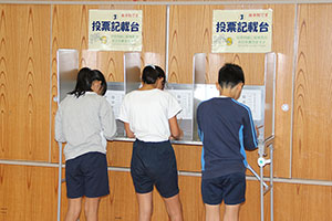 投票用紙に記入する児童