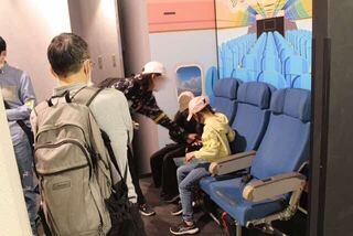 写真:飛行機の座席模型に座る様子