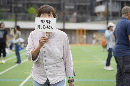 写真:カメラを持っている人と書いたボードを持っている人