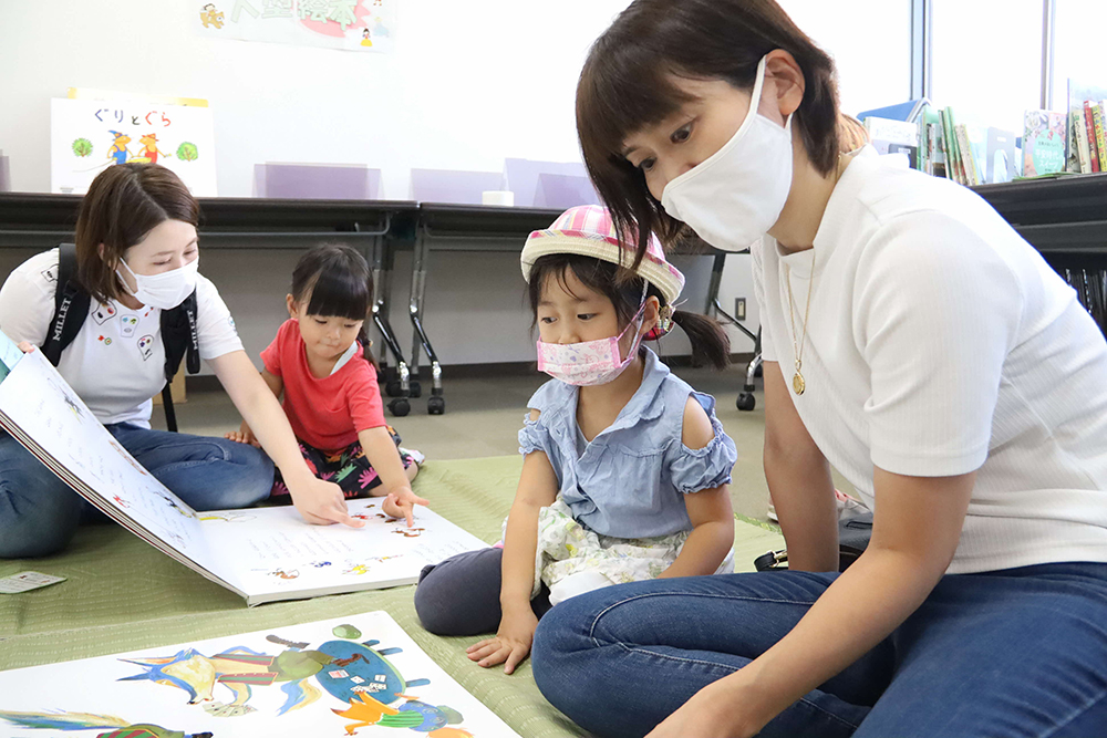 絵本を読み聞かせるお母さんと話を聞く子ども