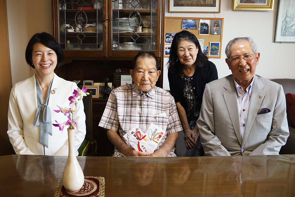 100歳の方と区長などが記念撮影の画像