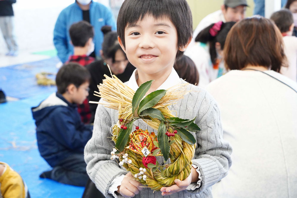 自作した正月飾りを持っている男の子の写真