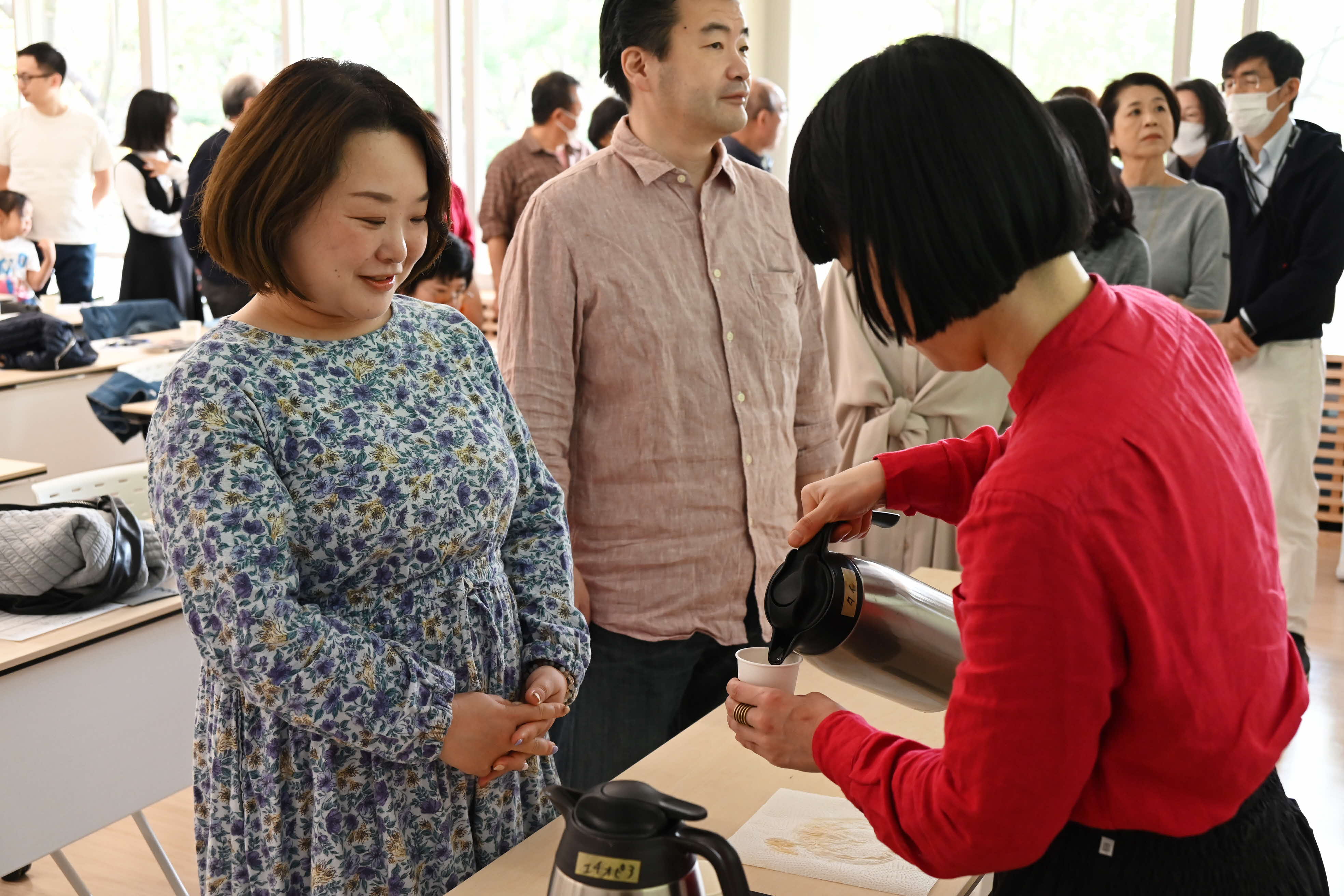 試飲のコーヒーを受け取っている女性の画像