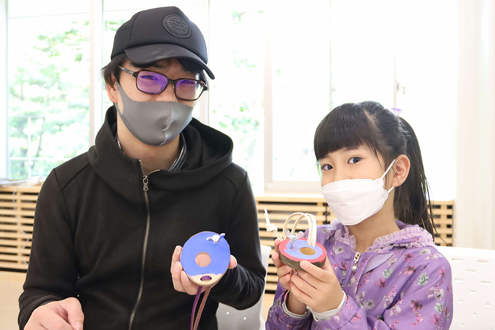 バードホイッスルを持って写真撮影するお父さんと子ども
