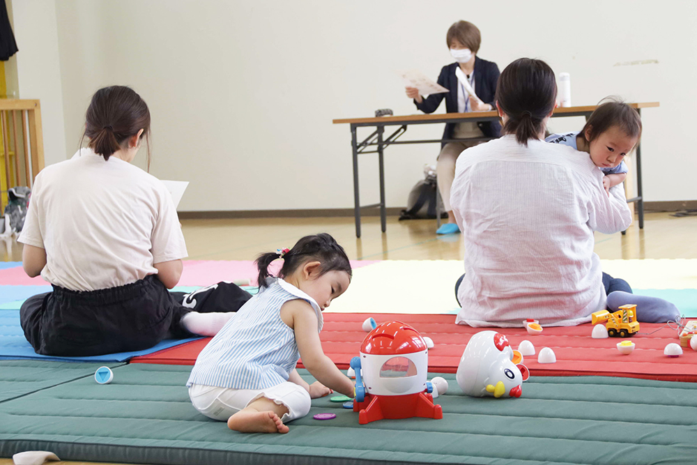 遊ぶ子どもと話を聞く保護者