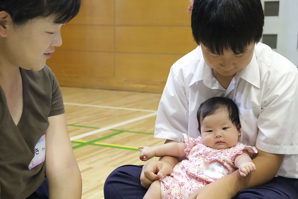 中学生の膝に座る赤ちゃんの画像