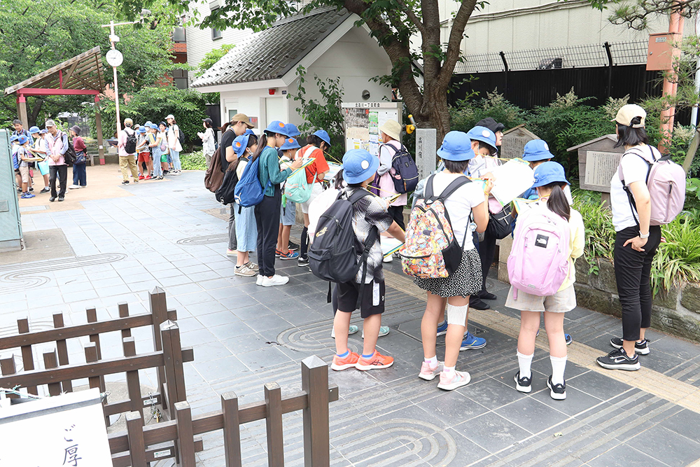 品川宿について説明するガイドと話を聞く児童たちの画像