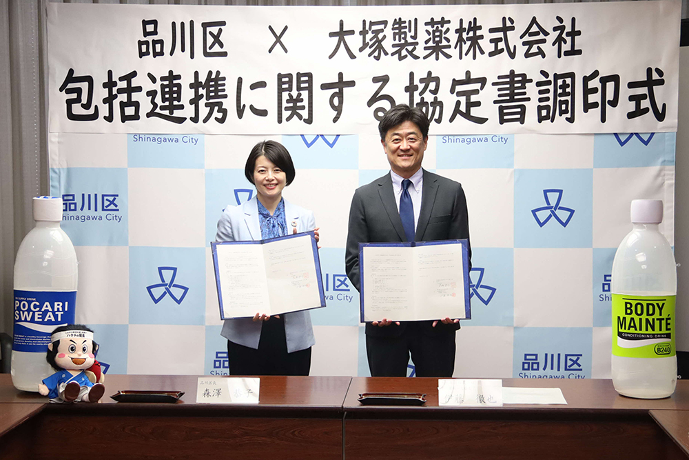 協定書を持ち記念撮影する森澤区長と大塚製薬の伊藤さんの画像