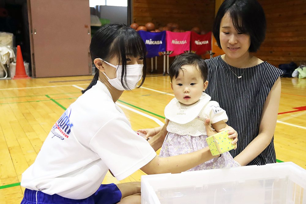 赤ちゃんとふれあう中学生の画像