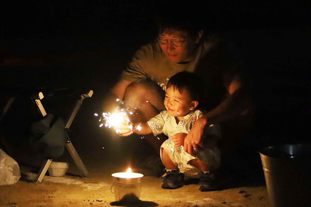 花火を楽しむ幼児と父親の画像