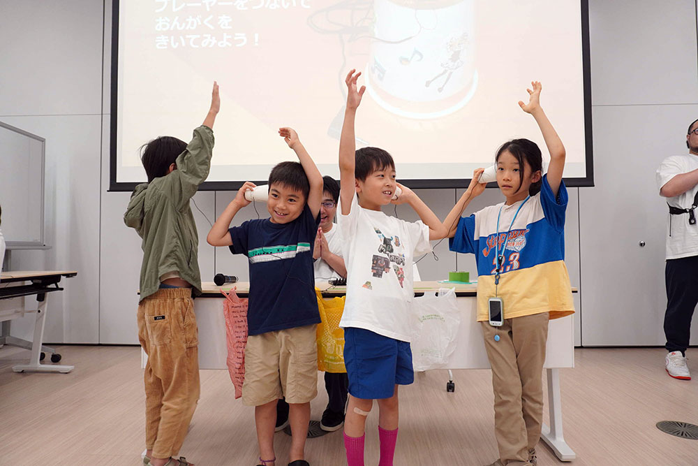 手作りスピーカーで音楽を聴く子どもたちの写真