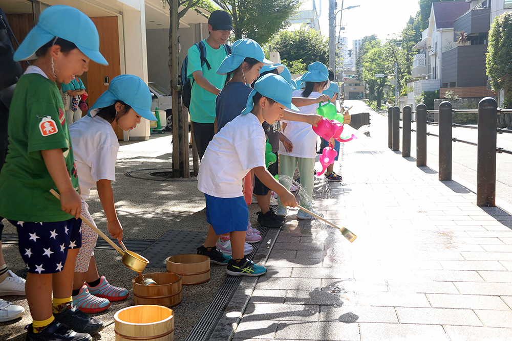 園児たちが打ち水を行っている写真