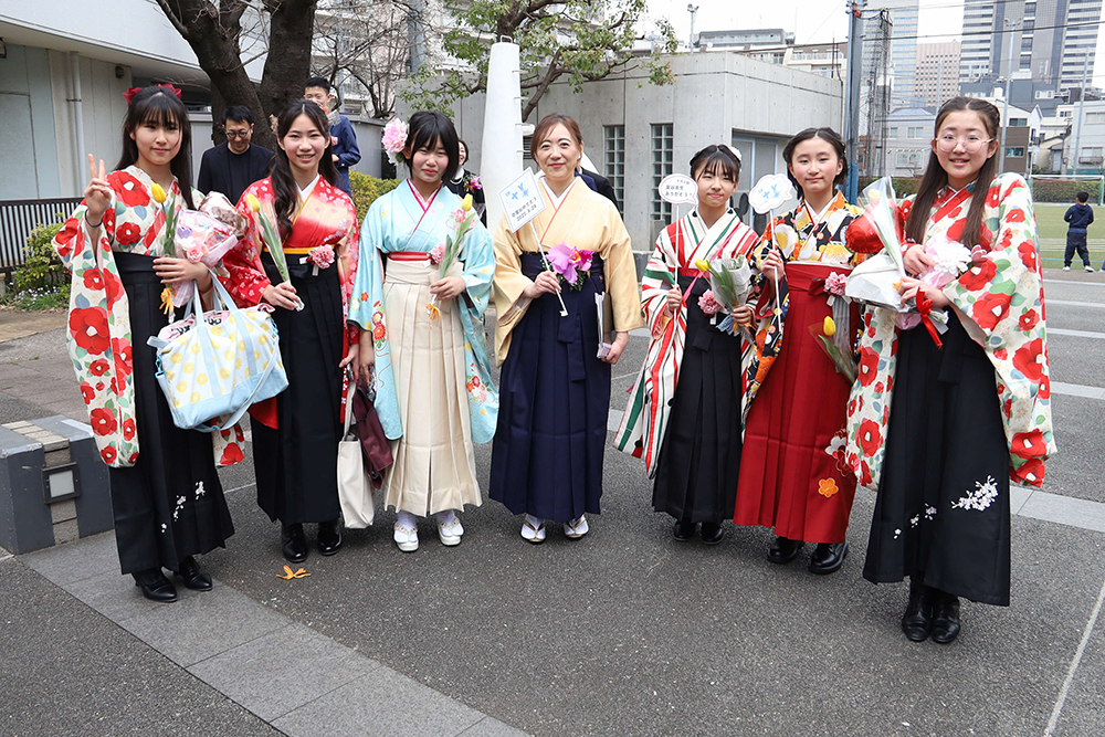 校門で先生と卒業生で写真を撮る画像