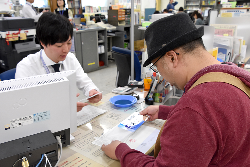 ご当地ナンバーの手続きをする男性