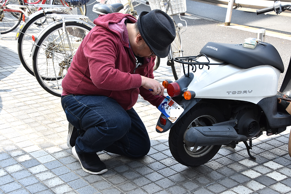 バイクにナンバーを取り付ける男性