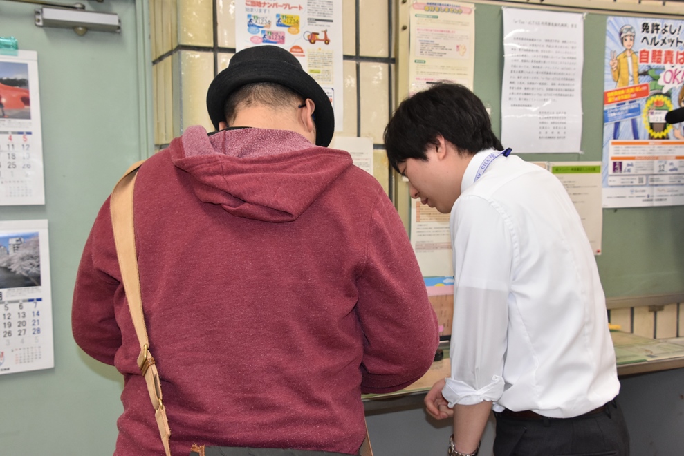 窓口で書類を書く男性