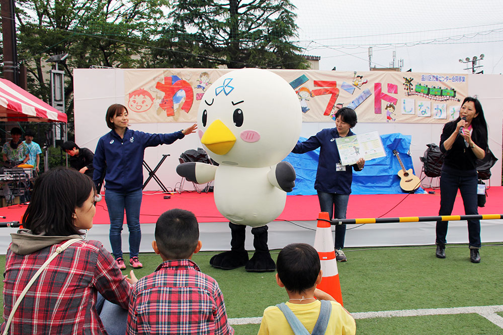 募る シナカモンと一緒にホッケー教室参加者募集PRする藤尾さん(左)