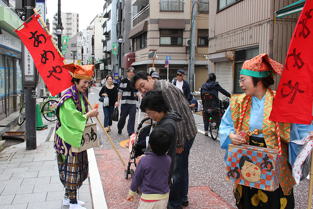 江戸時代の仮装をした人から雨をもらう子ども