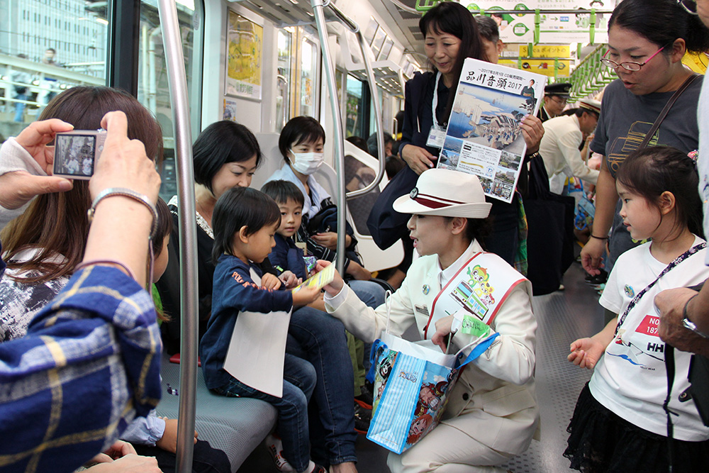 しながわ夢さん橋号でグッズ配付する一日駅長の岩本公水さん