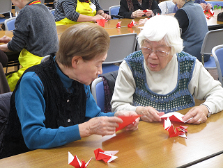 祝い鶴の折り方を教え合う中延地区の参加者