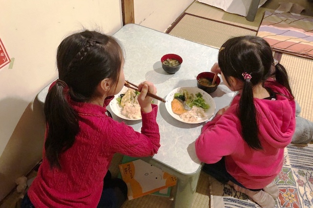 食事をする子どもたちの後ろ姿