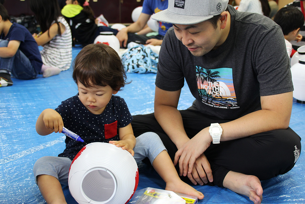 子どもが書いているようすを見守る父親