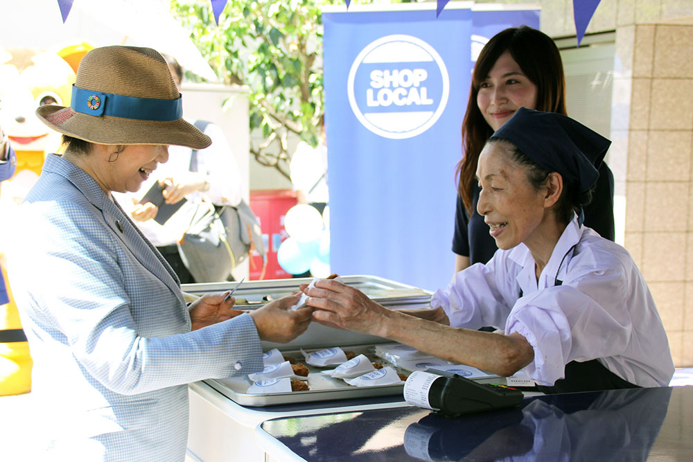 キャッシュレス決済でコロッケを購入する小池都知事