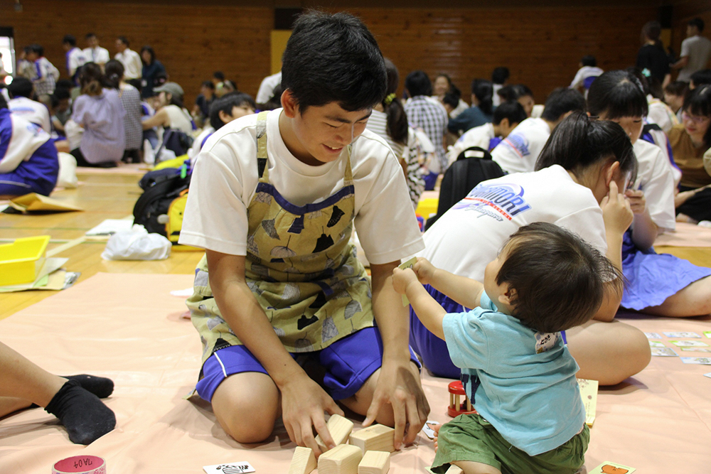 赤ちゃんに遊びをせがまれる男子生徒