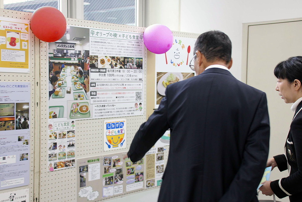 子ども食堂パネル展示をみる中村さんら