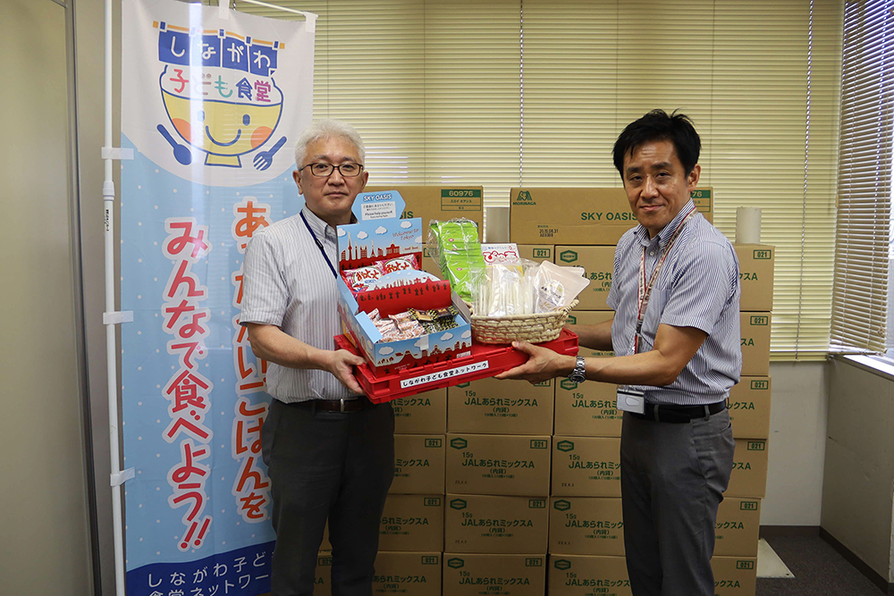 日本航空の職員より寄贈品を受け取る岡田室長