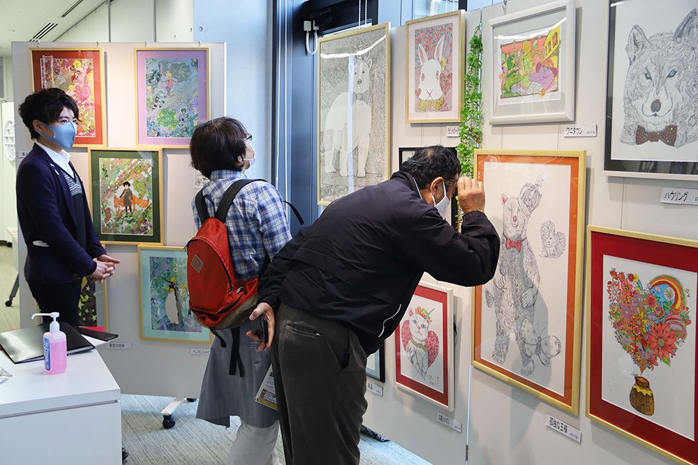 ペンで描かれた絵画を見る来場者の様子