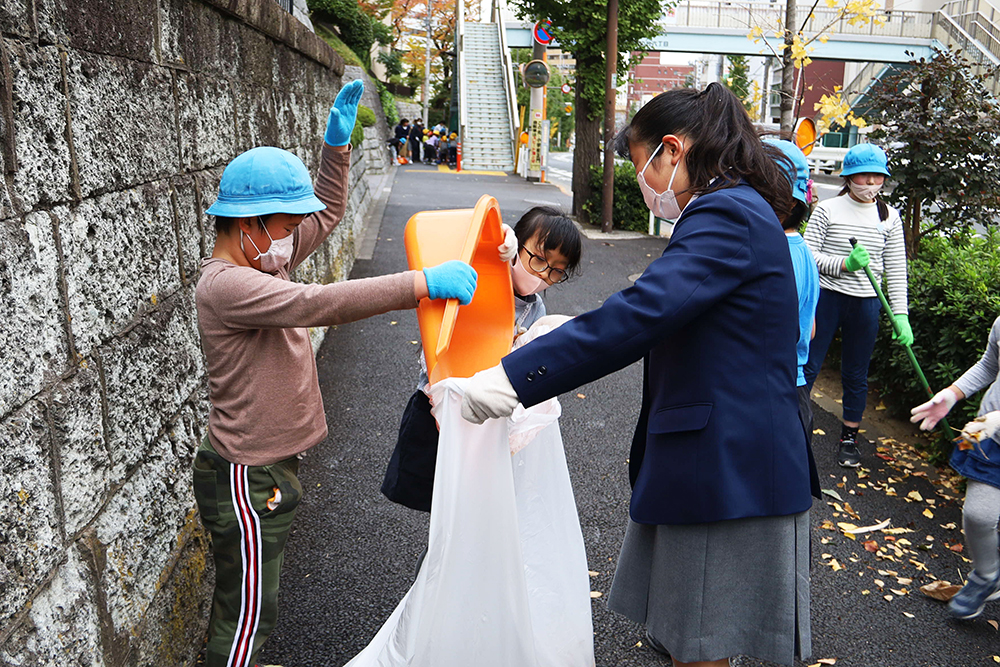 集めた落ち葉をごみ袋につめる