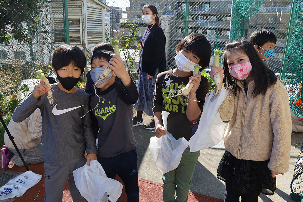 収穫した品川カブを手に記念撮影する児童たち