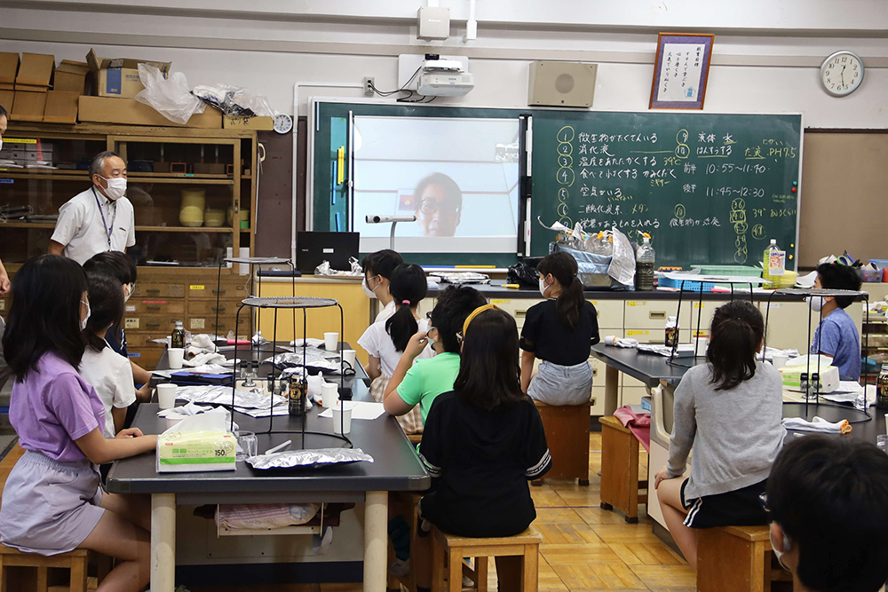 ZOOMで授業を行う多田先生 左に立っているのは宮原代表