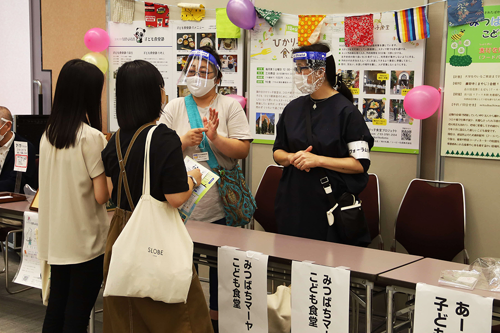 ブースで子ども食堂についての取り組みについて質問する女子大学生