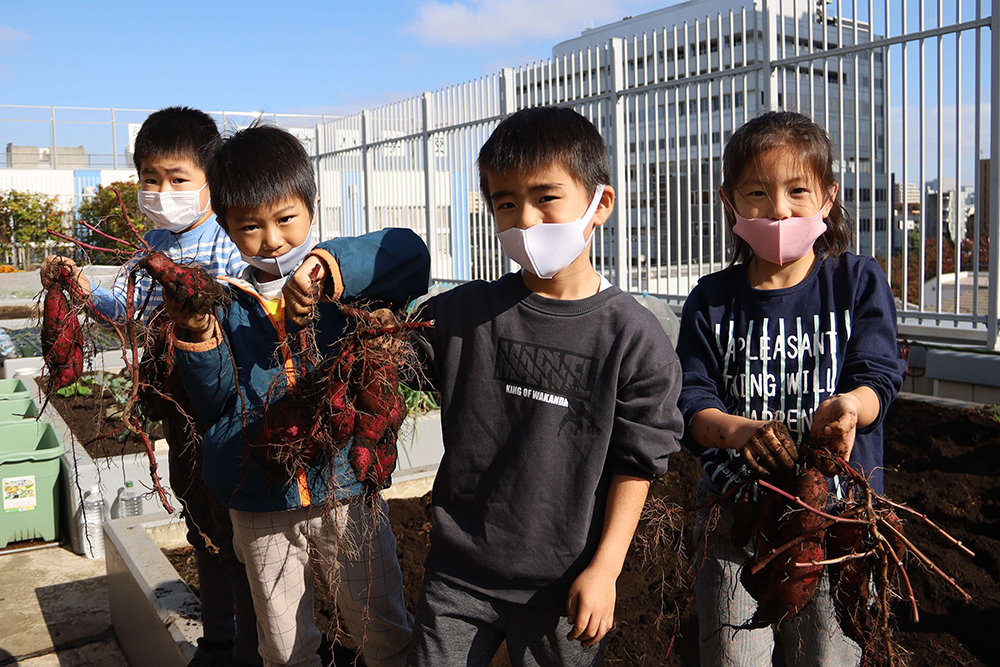 収穫したさつまいもを見せてくれる子どもたち