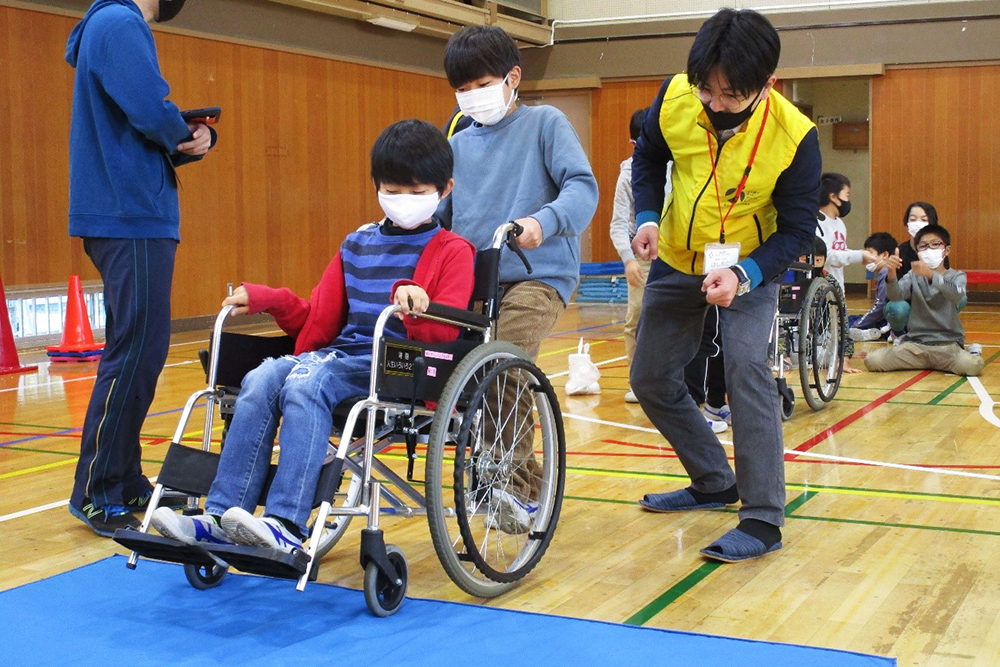 アドバイスを受けながら車いすを押す子どもたち