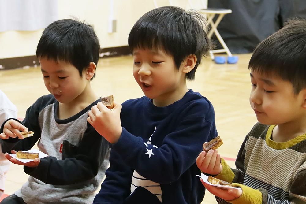 お茶菓子を嬉しそうにほおばる子ども