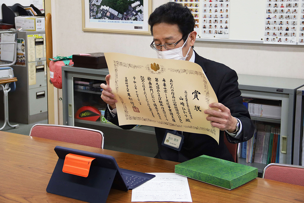 賞状をオンラインで見せる校長