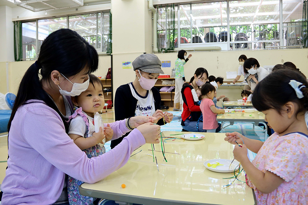 子どもを抱えながら工作する母親