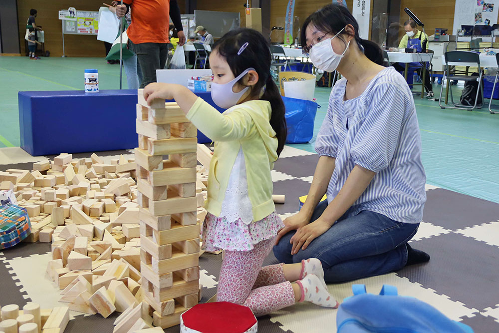 間伐材で作った積み木で遊ぶ親子