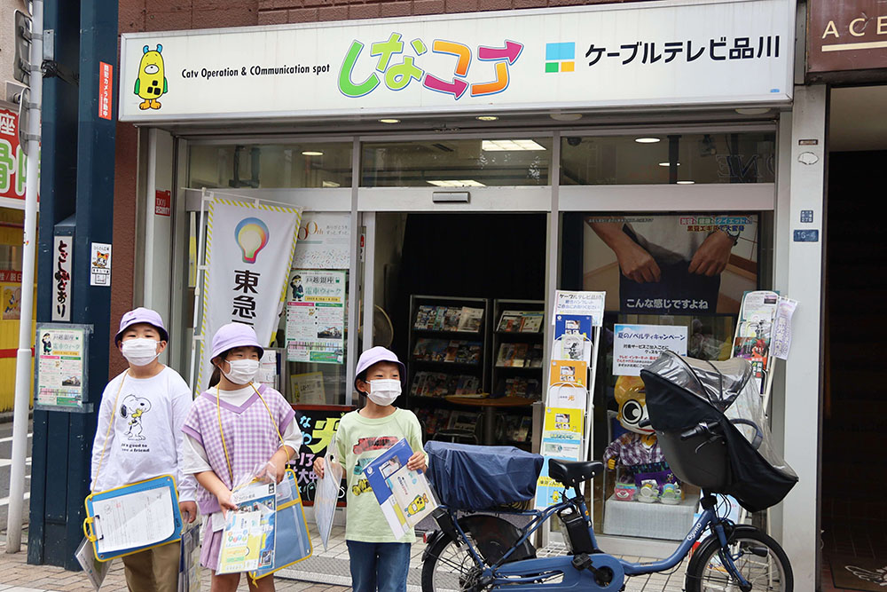 しなココ店舗の前で案内を配る子どもたち