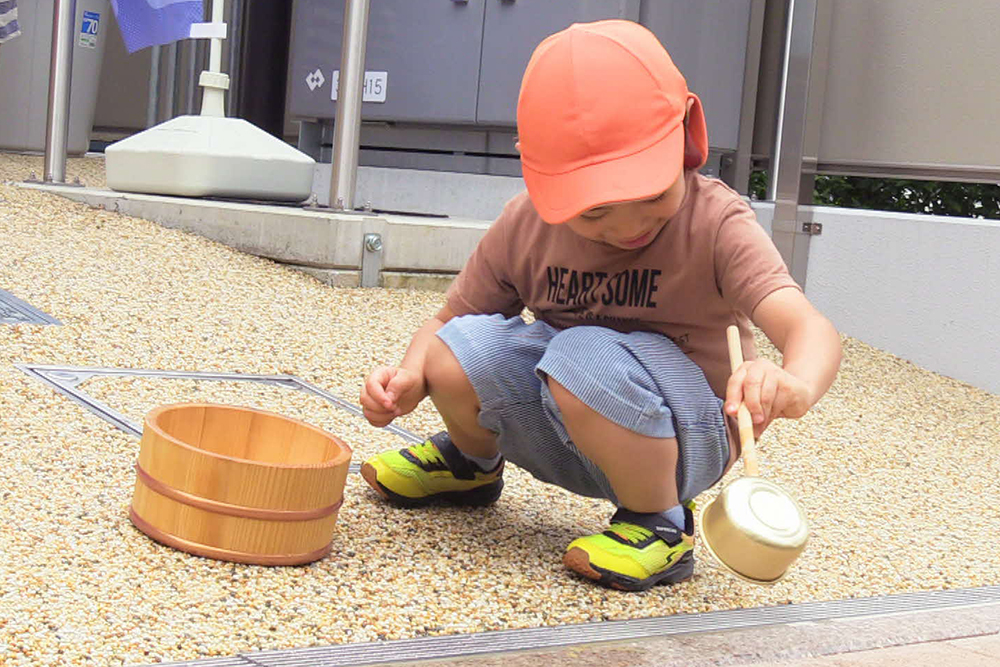 ひしゃくで打つ水する男の子