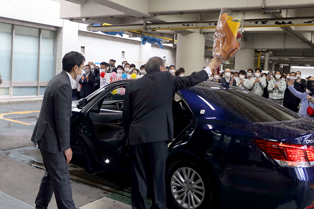 職員に向かって手を振りながら車に乗り込む区長