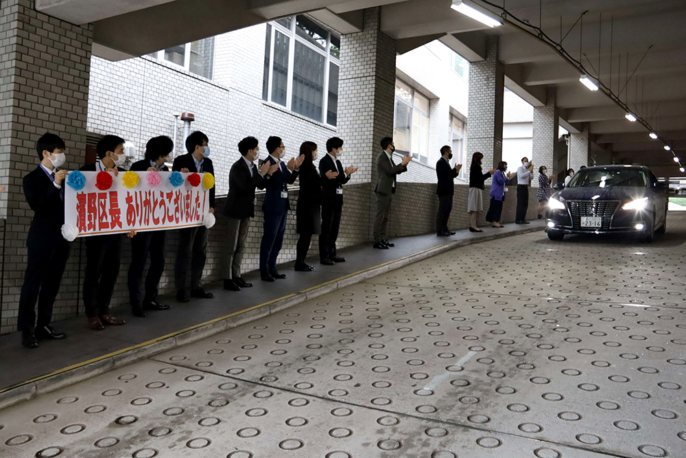 区長が乗る車を見送る職員ら