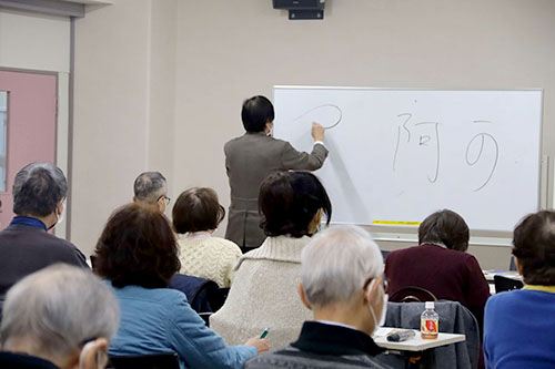 ホワイトボードを使用し説明をする中元さん