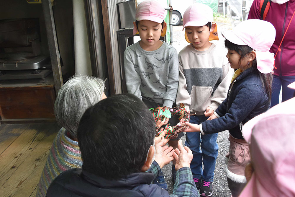 西五米店にリースを渡す園児たち